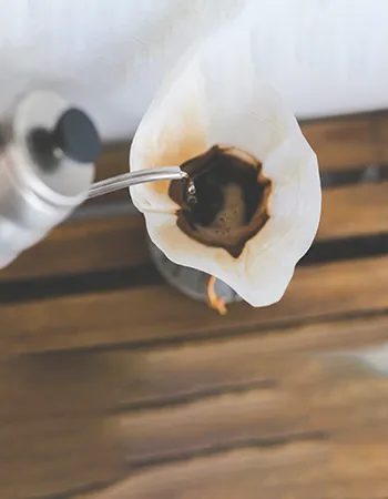 Filtered coffee being transferred into a new cup — an essential step in preparing coffee enema for effective detoxification and liver cleansing.