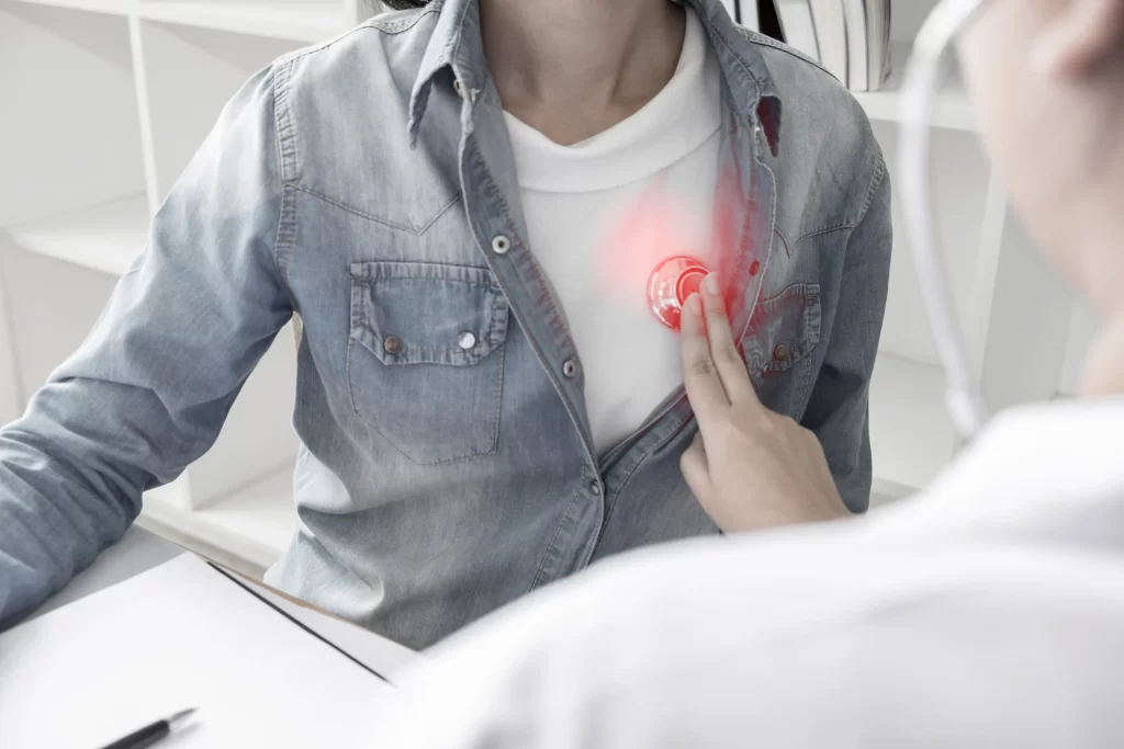 Doctor using stethoscope on patient’s heart and show red light— symbolizing EECP therapy to relieve angina and enhance heart function through improved blood flow.